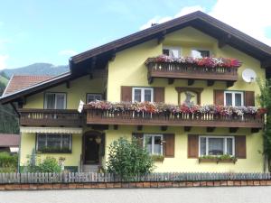a yellow house with a balcony with flowers on it at Haus zur Linde in Wagrain