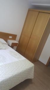 1 dormitorio con 1 cama con cabecero de madera en Apartamento Xardin, en Muxía