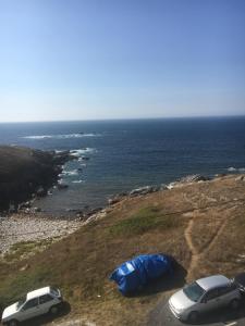 two cars parked on a hill next to the ocean at Apartamento Xardin in Muxia