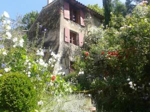 an old house with a pink window and flowers at Chambre d'Hôte Le Théron in Dieulefit