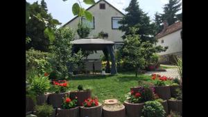 un giardino con fiori e ombrellone di fronte a una casa di Horváth Apartmanház a Szigliget