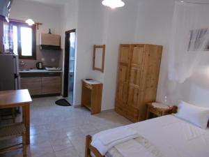 a bedroom with a white bed and a kitchen at Filoxenia in Skopelos Town