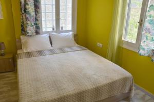 a bed in a yellow room with two windows at Athens historical center Love suite 2 in Athens