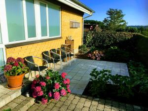 a patio with chairs and flowers in front of a house at 2 rooms, private kitchen, bathroom, and garden. in Viby