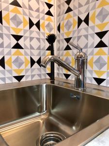 a stainless steel sink in a kitchen with a tile wall at ROOM 10 in Valmiera