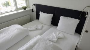 a white bed with white pillows and towels on it at 2 rooms, private kitchen, bathroom, and garden. in Viby