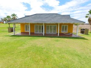 una pequeña casa amarilla con un gran patio en Del Bono Beach Complejo Bahia en Las Tapias