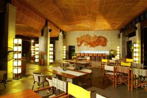 un restaurante con mesas y sillas en una habitación en Hansar Casuarina Cha am, en Puk Tian