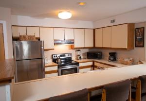 a kitchen with wooden cabinets and a stainless steel refrigerator at Mountain Lodge at Okemo in Ludlow