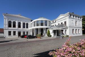 a white building with a car parked in front of it at Hotel Am Schloss Aurich in Aurich