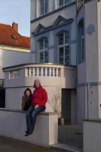 Un uomo e una donna seduti su un muro di fronte a un edificio di Villa Ida a Lubecca