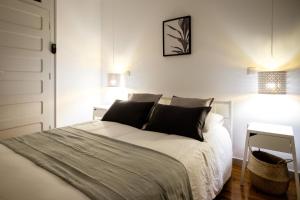 een wit bed met zwarte kussens in een slaapkamer bij Casa do Vento by Home Sweet Home Aveiro in Aveiro