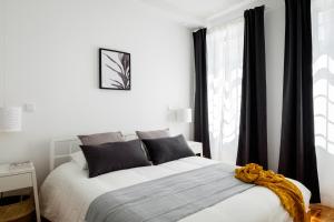 een witte slaapkamer met een bed en een raam bij Casa do Vento by Home Sweet Home Aveiro in Aveiro