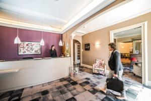 una mujer caminando por el vestíbulo de un hotel con equipaje en The Originals Boutique, Hôtel Normandie, Auxerre en Auxerre