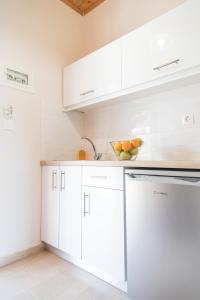 eine Küche mit weißen Schränken und einer Obstschale auf der Theke in der Unterkunft Nikos & Vivi Studios in Perivólion