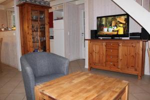 ein Wohnzimmer mit einem TV, einem Stuhl und einem Tisch in der Unterkunft Strandhaus Deichkrone in Baabe + 20 Fotos