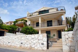 a large white house with a stone wall at Beachfront Apartment Nikol in Zaboric