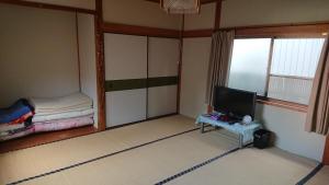 Tanabe - Hotel / Vacation STAY 15383 في تانابا: غرفة بها تلفزيون وسرير وطاولة