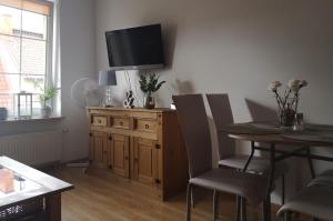 salon ze stołem i telewizorem na ścianie w obiekcie Apartament Boya w mieście Giżycko