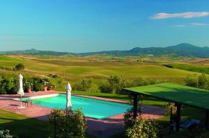 a swimming pool with umbrellas next to a field at Le Traverse in Pienza