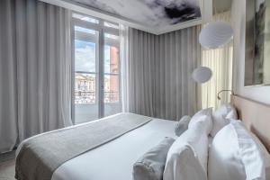 een slaapkamer met een groot wit bed met een raam bij Le Grand Balcon Hotel in Toulouse