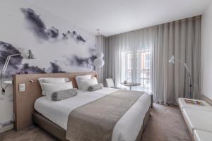 1 dormitorio con 1 cama grande y una pintura en la pared en Le Grand Balcon Hotel, en Toulouse