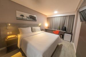 um quarto com uma grande cama branca e uma janela em Intercity Campina Grande Citymix em Campina Grande