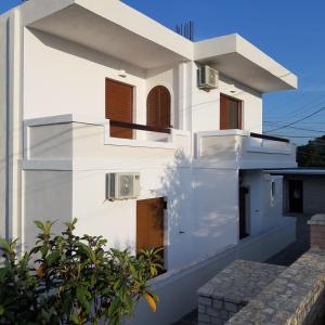 a white house with wooden doors and windows at Mihal Suites in Sarandë