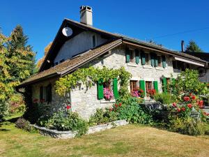 Paola paradise في Forel: منزل حجري صغير به مصاريع خضراء وزهور