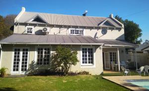a white house with a metal roof at Cottage Guesthouse in Pretoria