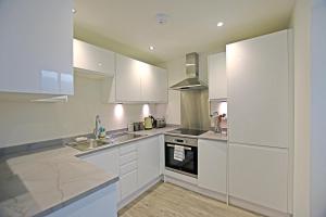 Una cocina con gabinetes blancos, un fregadero y una estufa. en Modern Commercial Street Maisonette, en Lerwick
