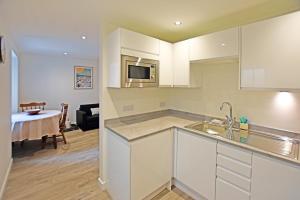 a kitchen with white cabinets and a living room at Modern Commercial Street Maisonette in Lerwick