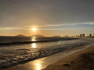 um pôr do sol na praia com a cidade ao fundo em Zona Dorada Mazatlan em Mazatlán