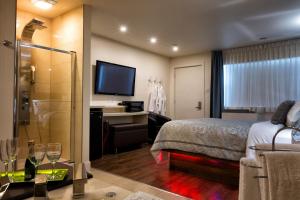 Habitación de hotel con cama, escritorio y TV. en Le Deauville Motel, en Trois-Rivières