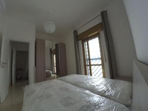 ein weißes Bett in einem Schlafzimmer mit einem großen Fenster in der Unterkunft Villa Blu - Torre Ovo in Monacizzo