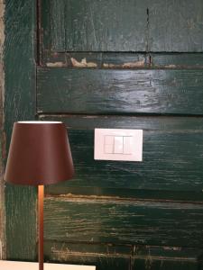 a lamp on a table next to a green door at Squisleep in San Daniele del Friuli