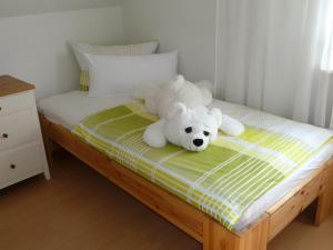 un osito de peluche blanco sentado en una cama en Helle 70 qm Ferienwohnung mit herrlichem Blick, en Teningen