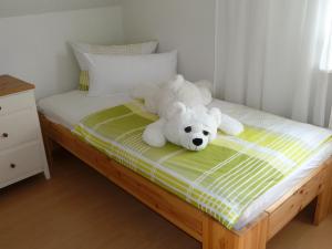 un orsacchiotto bianco seduto su un letto di Helle 70 qm Ferienwohnung mit herrlichem Blick a Teningen