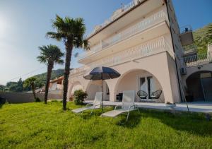 une maison avec deux chaises et un parasol dans l'herbe dans l'établissement Apartments Blue Horizon, à Mlini