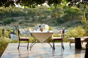 uma mesa e duas cadeiras num deque de madeira em Ivory Wilderness River Rock Lodge em Klaserie Private Nature Reserve