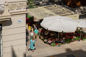 eine Aussicht auf einen Blumenmarkt mit einer Frau, die an einem Regenschirm vorbeigeht in der Unterkunft Soho Apartment Principal Avenue in Málaga
