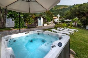 a hot tub in a yard with chairs and an umbrella at Ischia Dream Sunset in Ischia