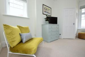 ein Wohnzimmer mit einem gelben Sofa und einer Kommode in der Unterkunft B&B@no2 in Sheringham