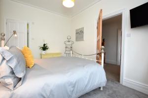 a white bedroom with a white bed and a television at B&B@no2 in Sheringham