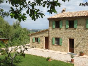 una vista exterior de una casa de piedra con persianas verdes en B&B Casa Cuccagna, en Fratte Rosa