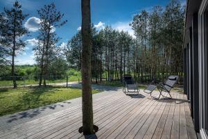 2 sillas sentadas en una terraza de madera junto a un árbol en Naturalny domek z banią ruską, en Siedliszcze