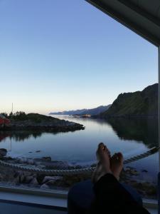 a person laying on a window looking out at a lake at Lofotveggen Panorama in Ballstad