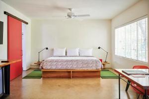 a bedroom with a bed and a desk and a window at Hotel San Jose in Austin