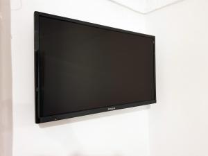 TV de pantalla plana colgada en una pared blanca en Anema By The Sea Guesthouse en Karlovasi