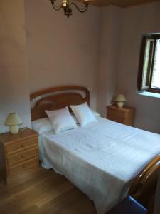 um quarto com uma cama grande com lençóis brancos e almofadas em Casa Valentina em Villar de Otero